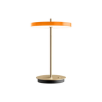 Cordless rechargeable LED table lamp, brass base, in orange, front view
