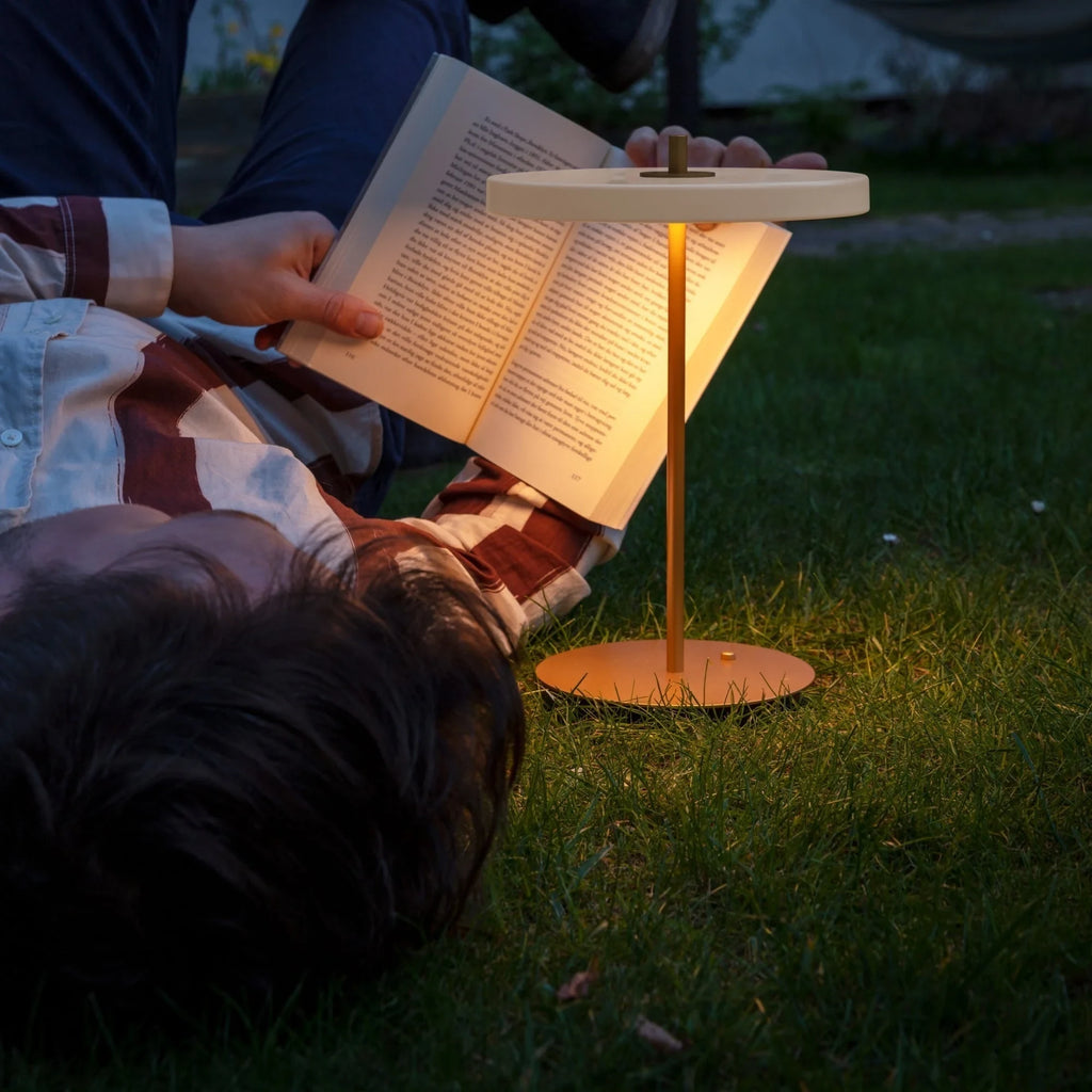 Cordless rechargeable LED table lamp, brass base, lit for reading at dusk