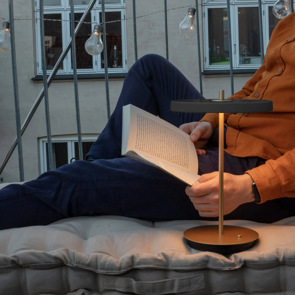 Cordless rechargeable LED table lamp, brass base, in use at home