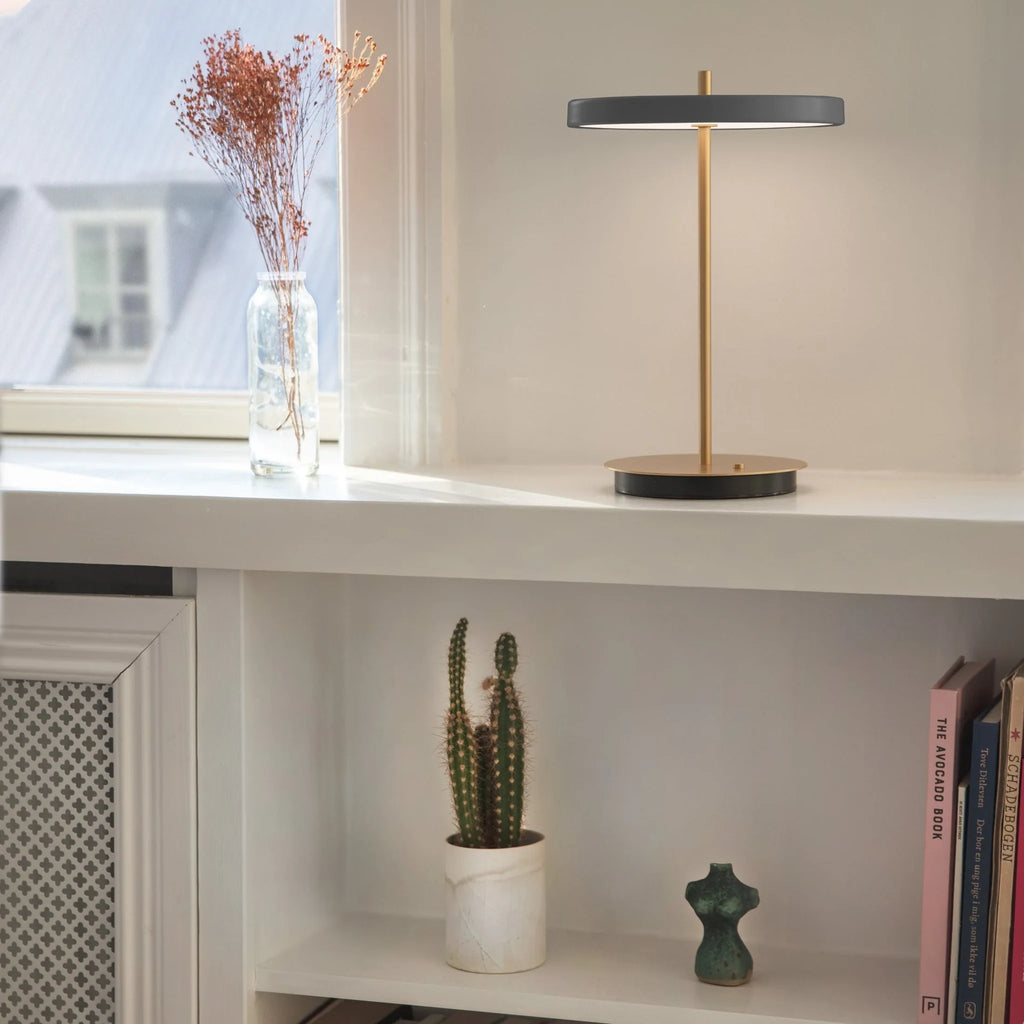 Cordless rechargeable LED table lamp, brass base, in use at home
