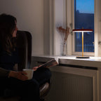 Cordless rechargeable LED table lamp, brass base, in use at home