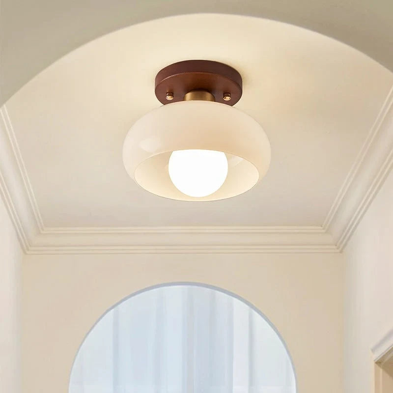 Cream glass flush ceiling light, lit below a white ceiling