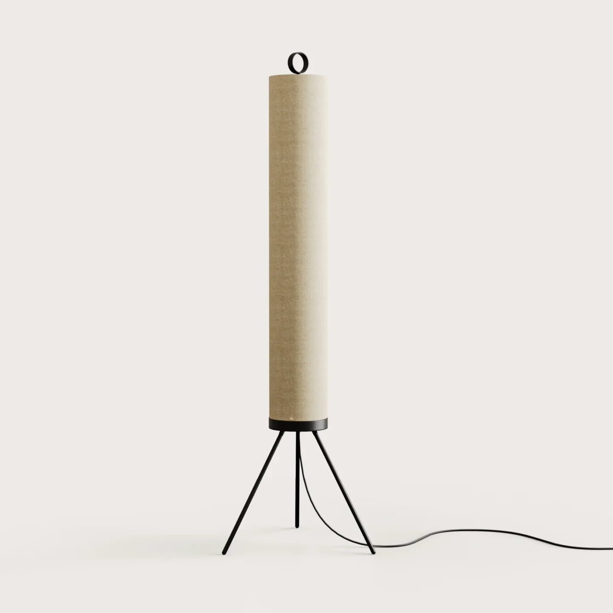 Cream linen tube floor lamp with black tripod base, against a plain wall