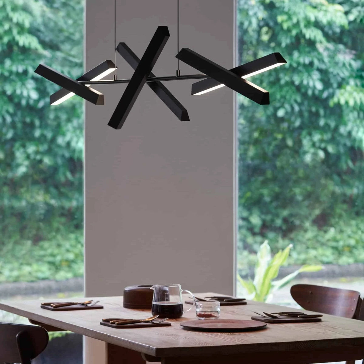 Crossed bar linear LED pendant, in black above a dining table
