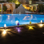 Crystal-effect rechargeable table lamp, several colours lit beside a pool at night