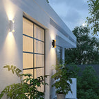 Curved up and down outdoor wall light, lit on a wall