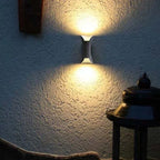 Curved up and down outdoor wall light, lit on a wall