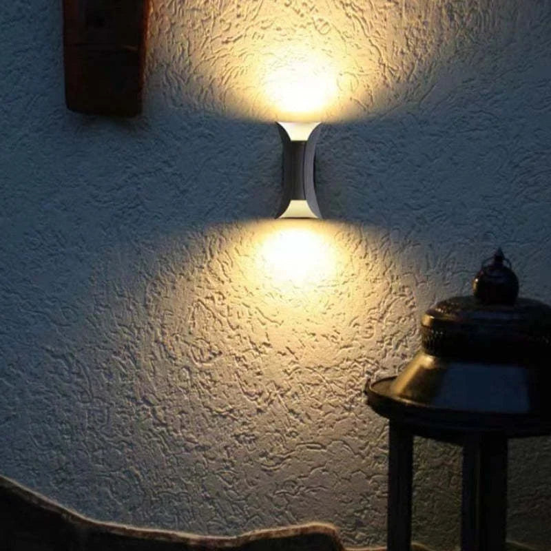 Curved up and down outdoor wall light, lit on a wall