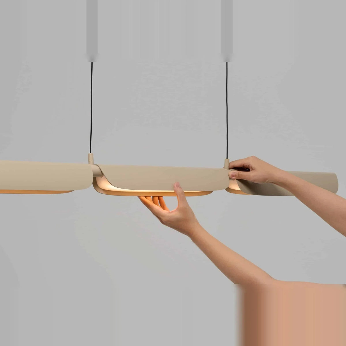 Curved shade linear LED pendant, shade being adjusted by hand