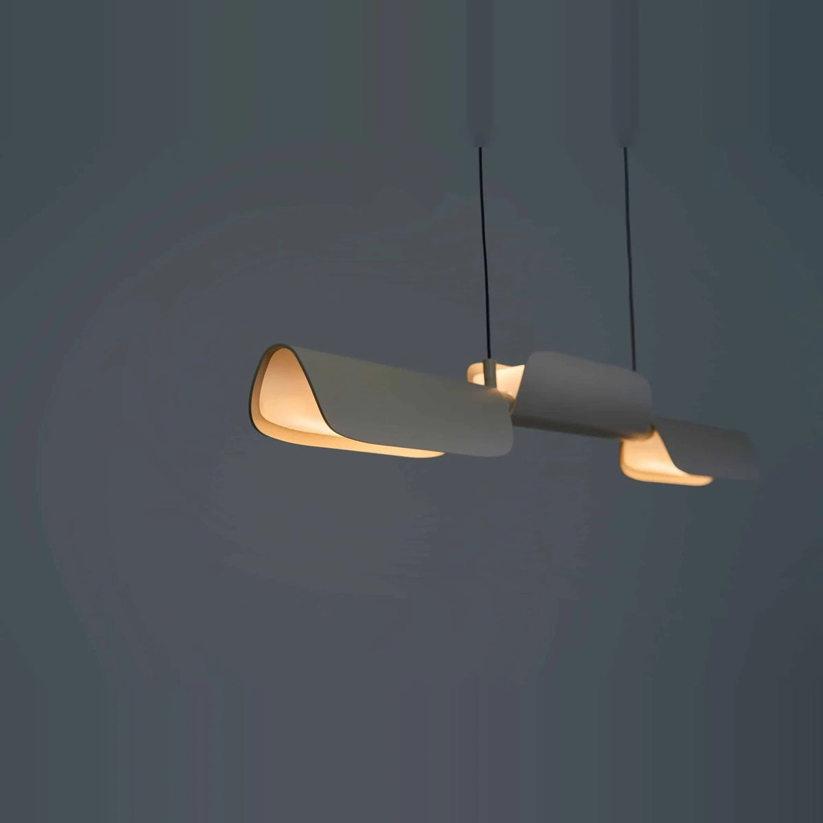 Curved shade linear LED pendant, in oatmeal against a dark wall