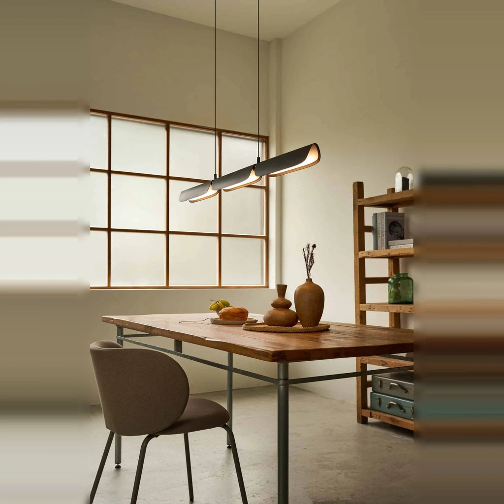 Curved shade linear LED pendant, above a table by a window