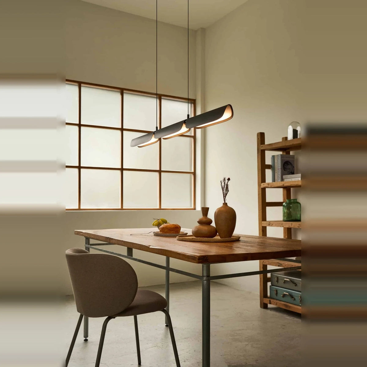 Curved shade linear LED pendant, above a table by a window