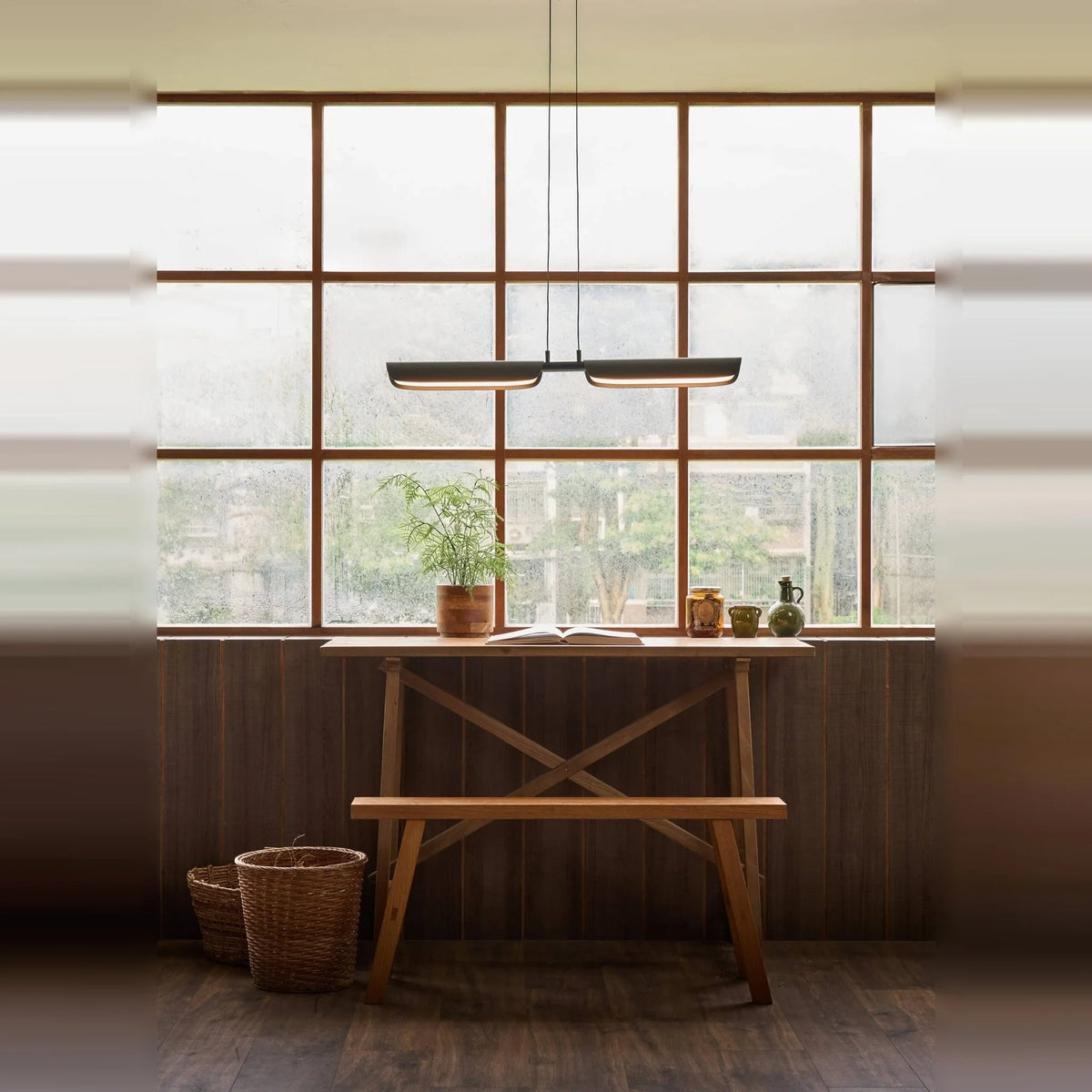 Curved shade linear LED pendant, above a wooden table