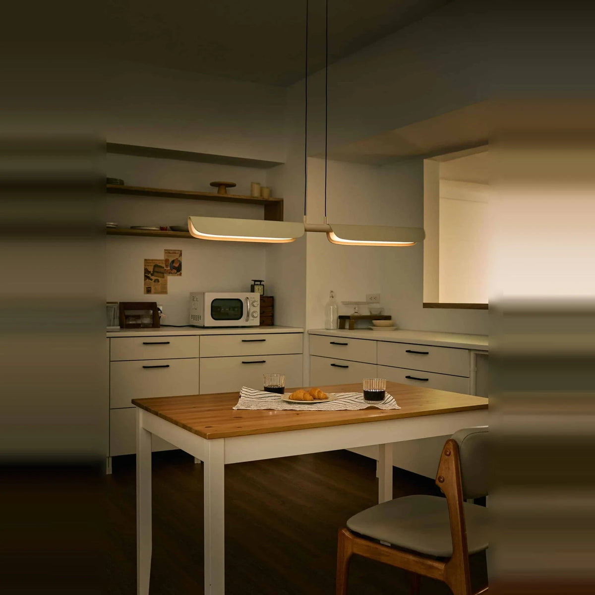 Curved shade linear LED pendant, above a kitchen table