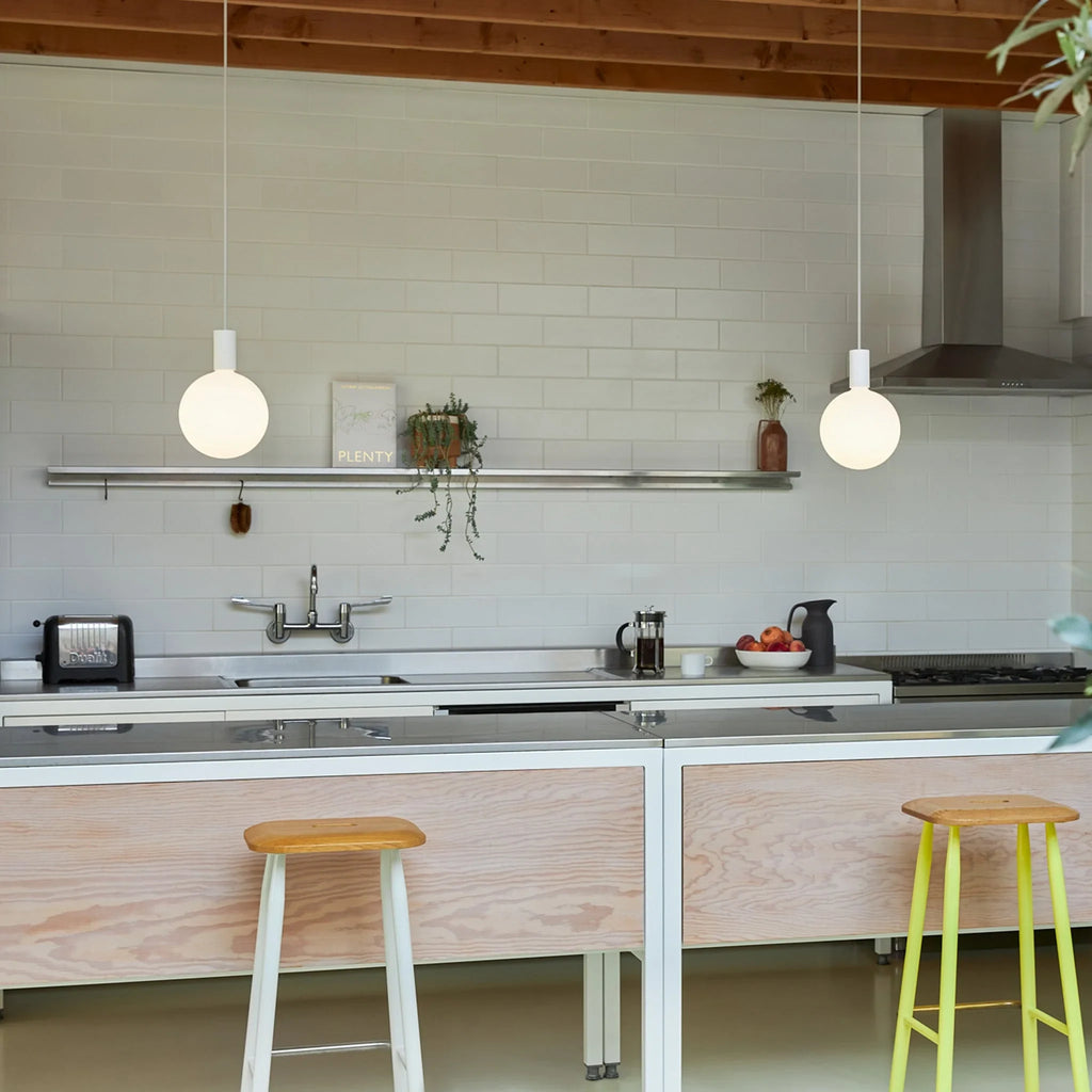 Cylinder pendant with matt white globe bulb, chalk, two above a kitchen counter