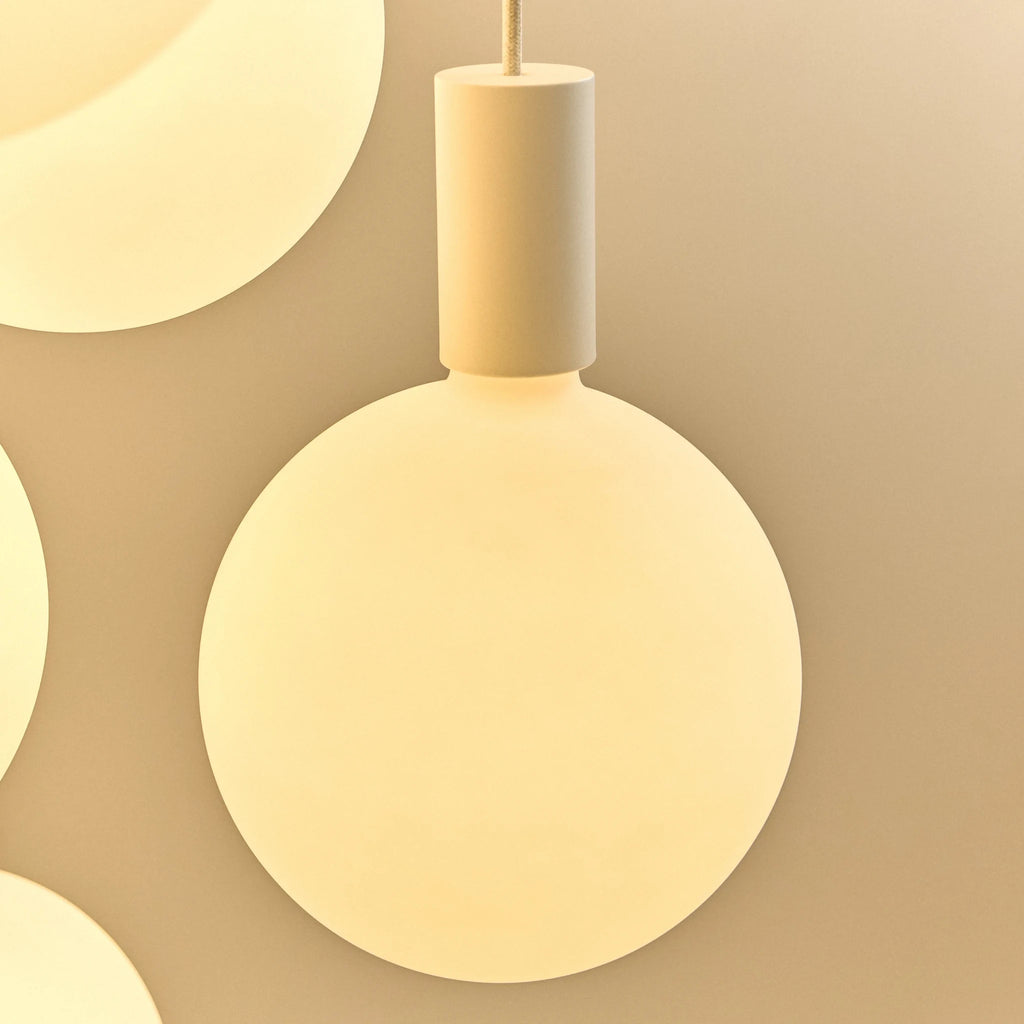 Cylinder pendant with matt white globe bulb, chalk, close-up of the lit bulb and holder