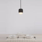 Dark concrete and glass mini pendant, above a table set for a meal