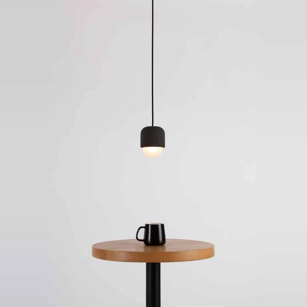 Dark concrete and glass mini pendant, above a side table with a mug