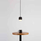 Dark concrete and glass mini pendant, above a side table with a mug