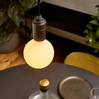 Dim-to-warm globe pendant, graphite, close-up of the lit globe above a dining table