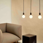 Dim-to-warm globe pendant, graphite, three together above a living room