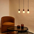 Dim-to-warm globe pendant, walnut, three together above a coffee table