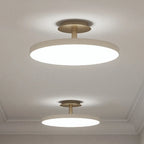 Disc LED ceiling light with brass stem, two sizes in a pale room