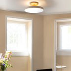 Disc LED ceiling light with brass stem, in pearl white, in a room with windows