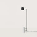 Dome shade reading floor lamp with white marble base, in a room with a bench and framed art