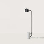 Dome shade reading floor lamp with white marble base, in a room with a bench and framed art