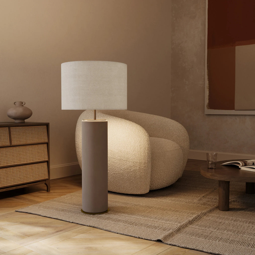 Extra-tall hand-painted ceramic cylinder table lamp, in grey, beside a lounge chair, with a shade (sold separately)