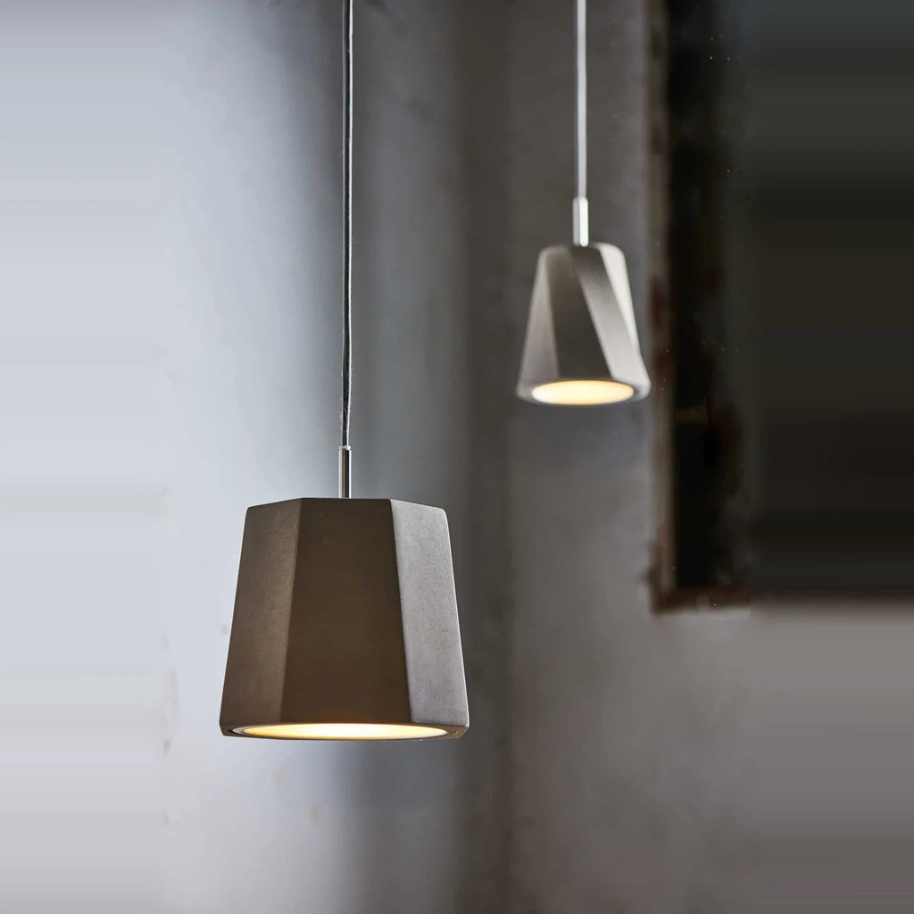 Faceted concrete pendant, lit against a grey wall