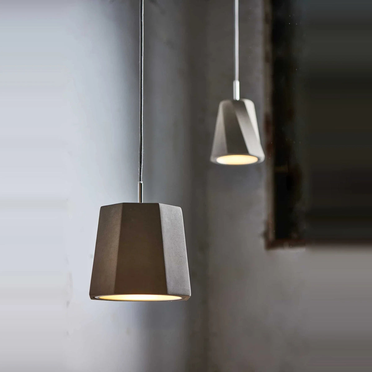 Faceted concrete pendant, lit against a grey wall