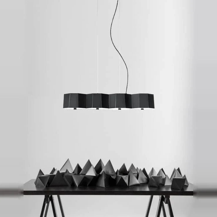 Faceted metal linear pendant, in black above a sculptural table display