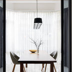 Faceted metal linear pendant, end-on view above a dining table
