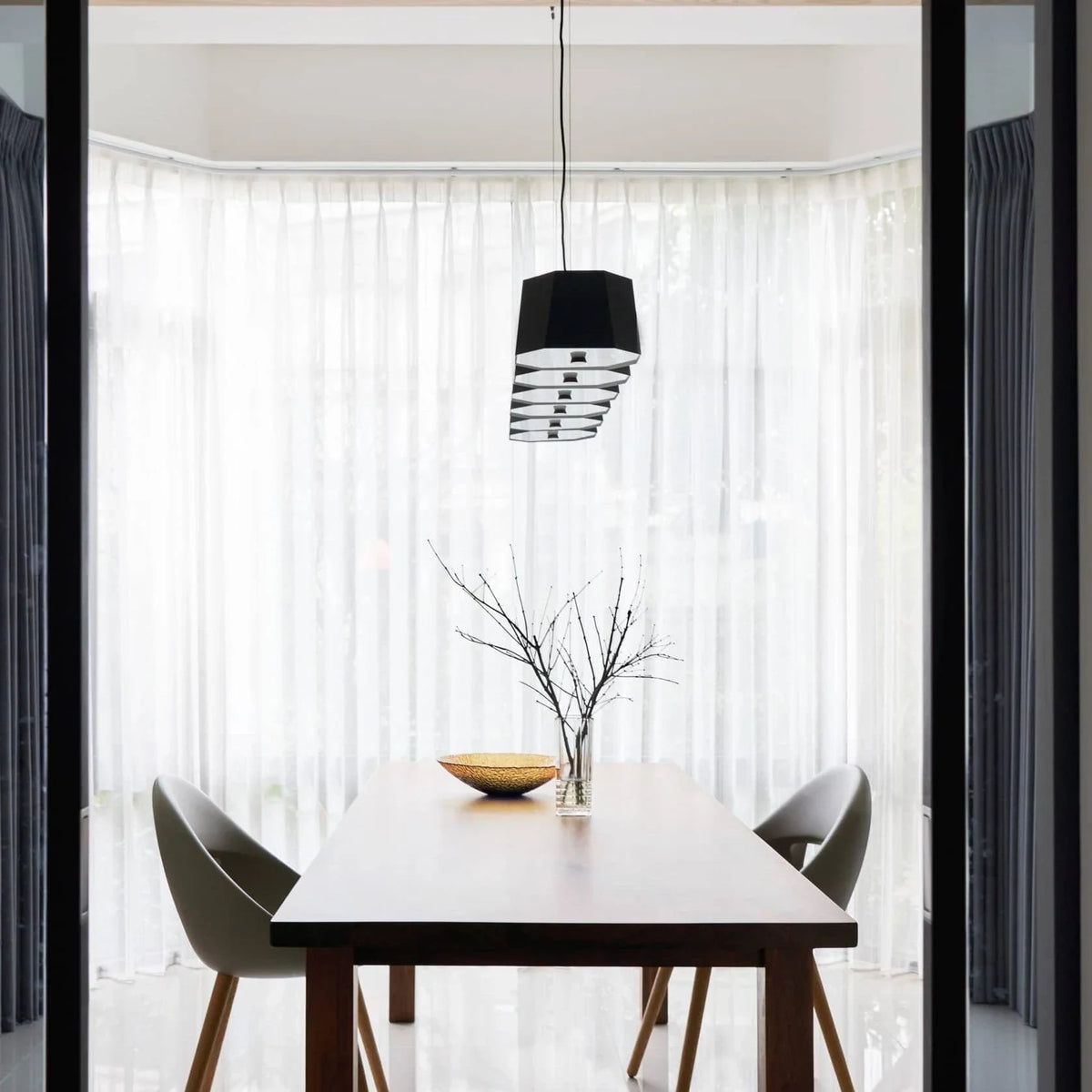 Faceted metal linear pendant, end-on view above a dining table