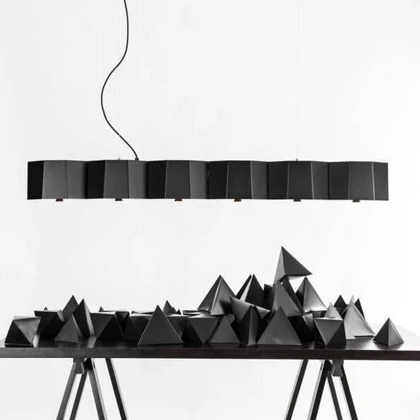 Faceted metal linear pendant, in black above a sculptural table display