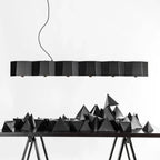 Faceted metal linear pendant, in black above a sculptural table display
