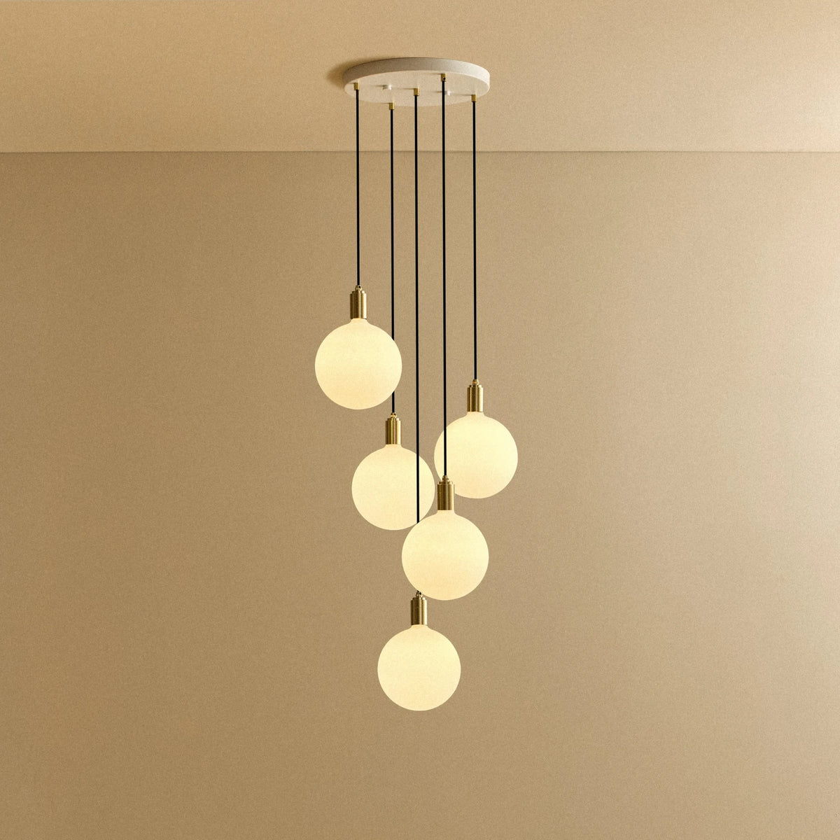 Five-drop cluster pendant with opal globe bulbs, brass, lit, on a white canopy