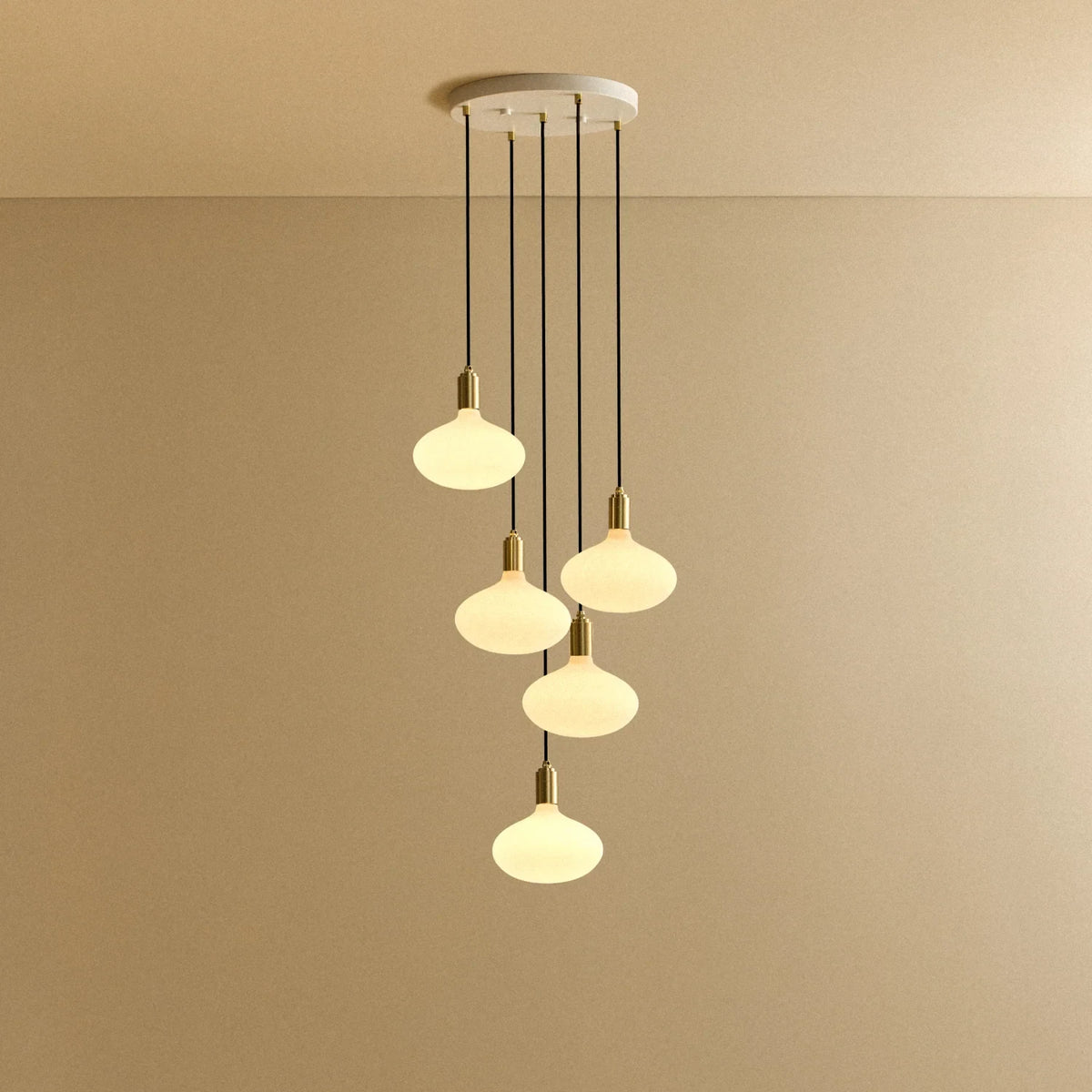Five-drop cluster pendant with opal oval bulbs, brass, lit, on a white canopy