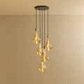 Five-drop cluster pendant with tinted sculptural bulbs, graphite, lit, against a plain wall