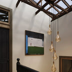 Five-drop cluster pendant with tinted sculptural bulbs, graphite, in a stairwell under a skylight