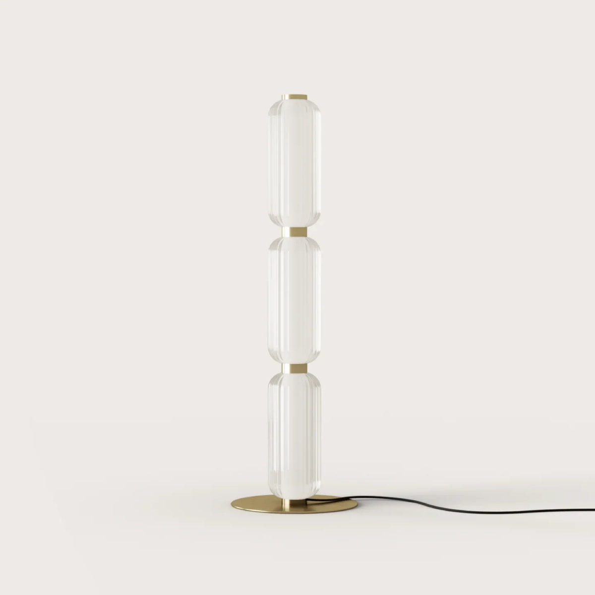 Fluted glass capsule floor lamp with three segments, lit, against a plain wall
