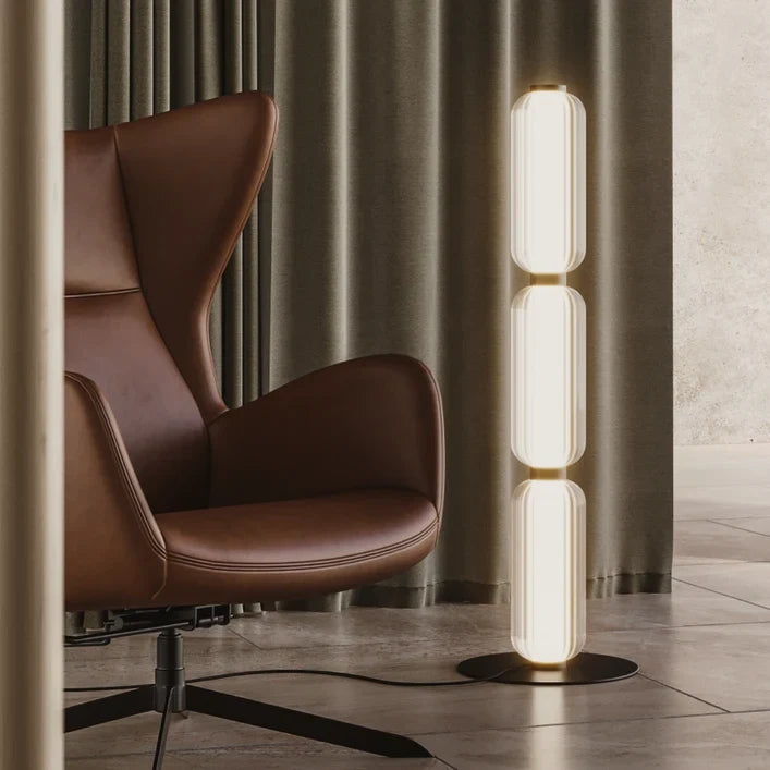 Fluted glass capsule floor lamp with three segments, beside a leather armchair
