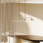 Four-dome linear glass pendant with integrated LED, above a long dining table