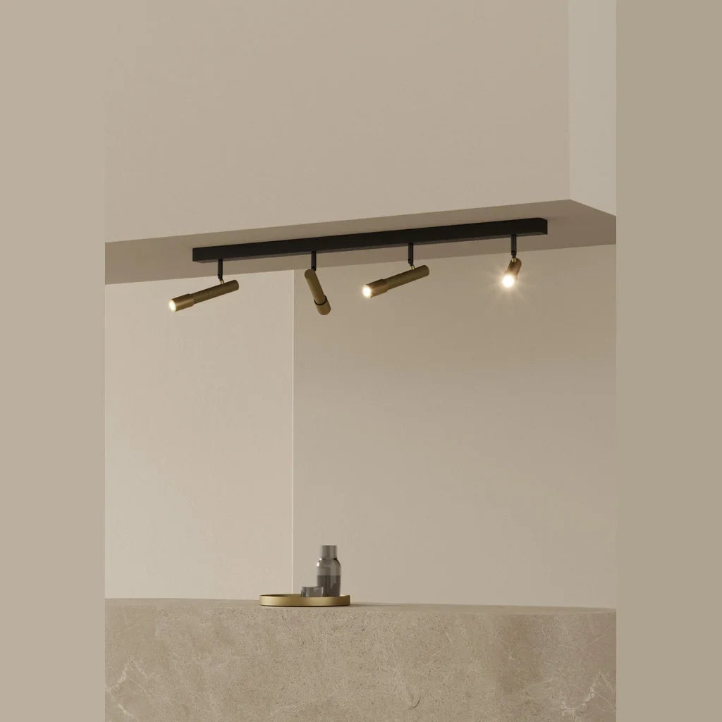 Four-spot ceiling bar light, with gold spots, in a room with a stone counter