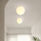 Frosted glass globe wall light, two sizes lit on a wall