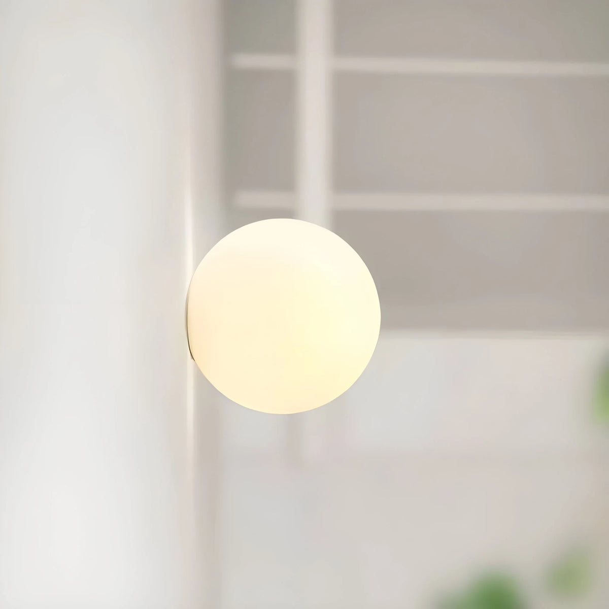 Frosted glass globe wall light, lit, side view