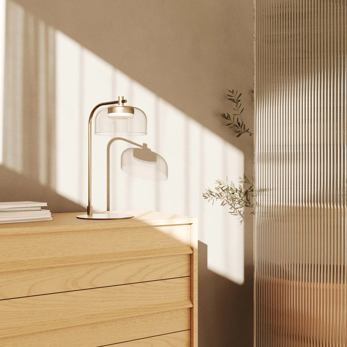 Arc table lamp with glass dome shade, on a chest of drawers in sunlight