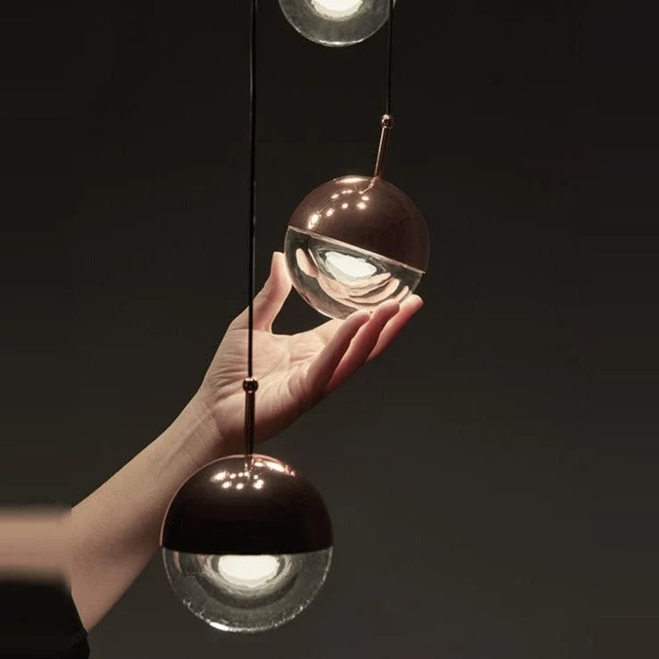 Glass globe cluster pendant, three lights, close-up, one globe held in a hand